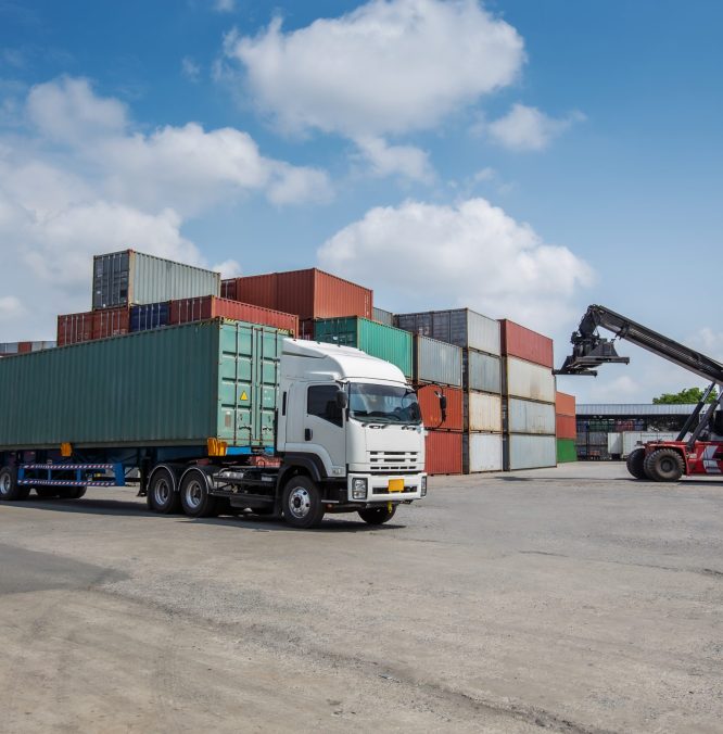 A red container forklift loads a cargo container onto a white truck in a busy shipping yard. Surrounded by stacked containers, the scene represents global logistics, trade, and freight transportation.